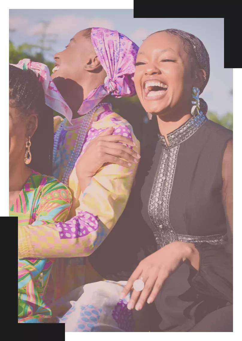 Three black women laughing beside each other.